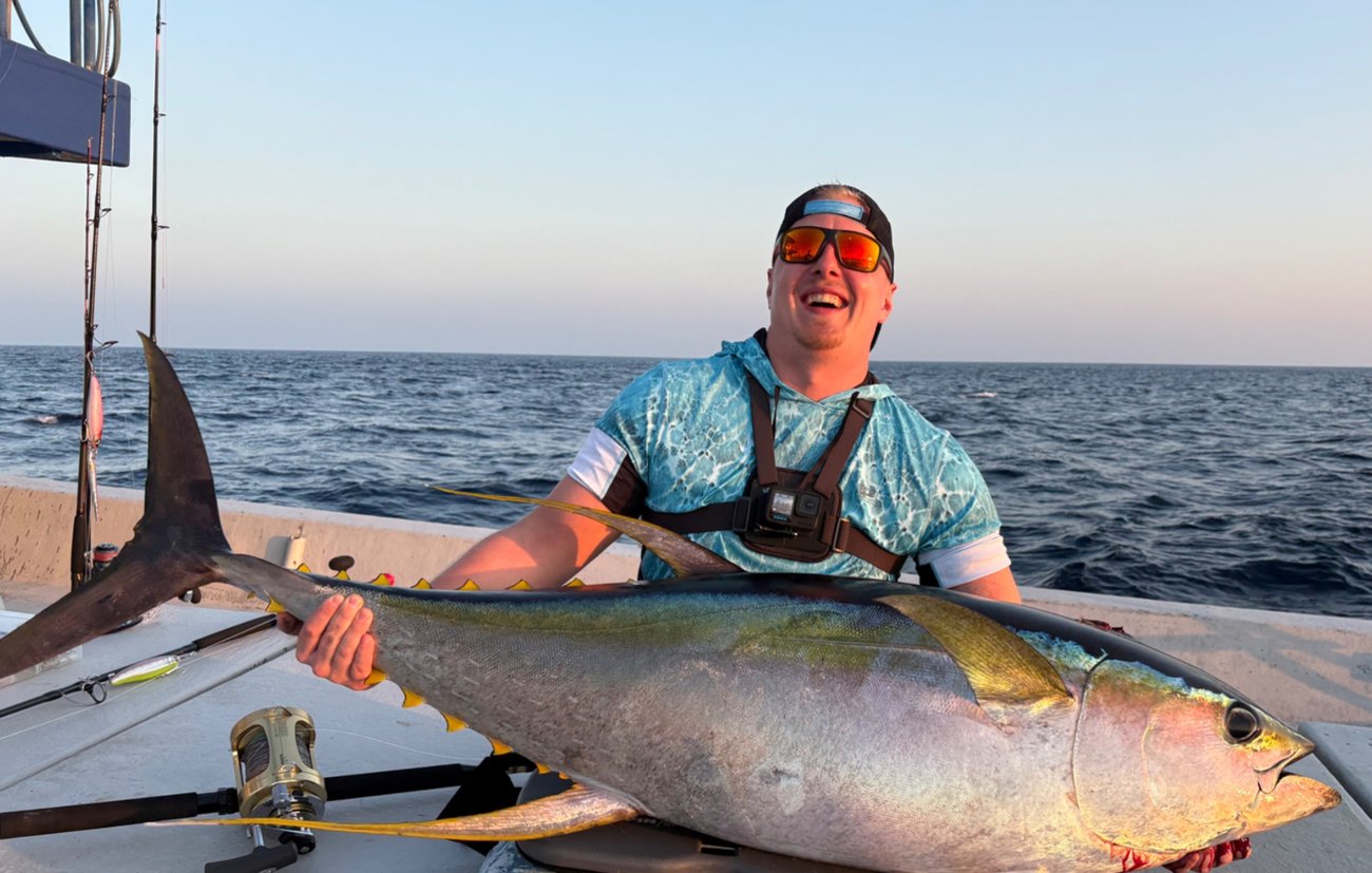 Angler holding a large yellowfin tuna on a SALTRIPS boat at sunset